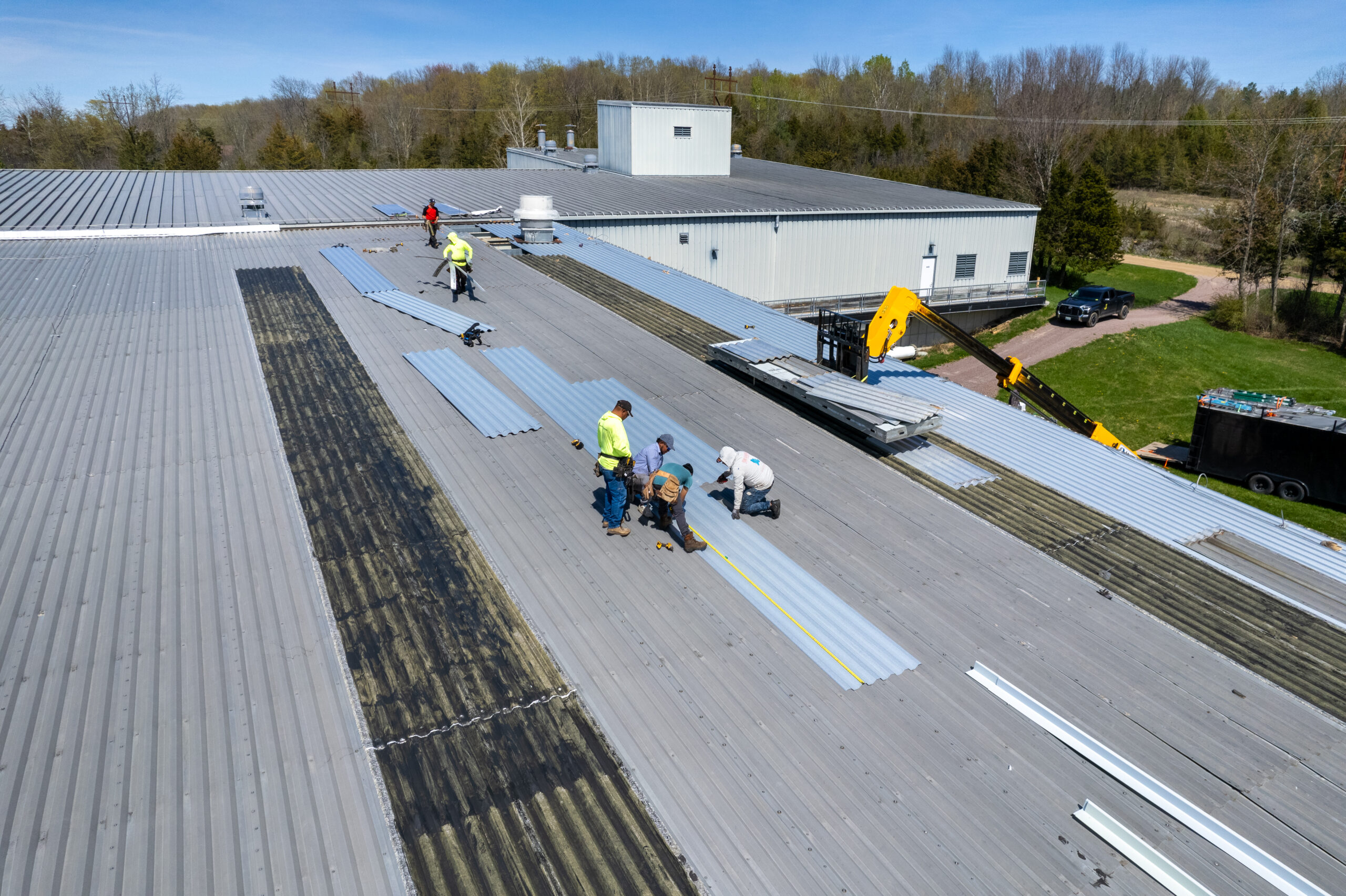 Roofers working on a metal corrugated roof in Vermont