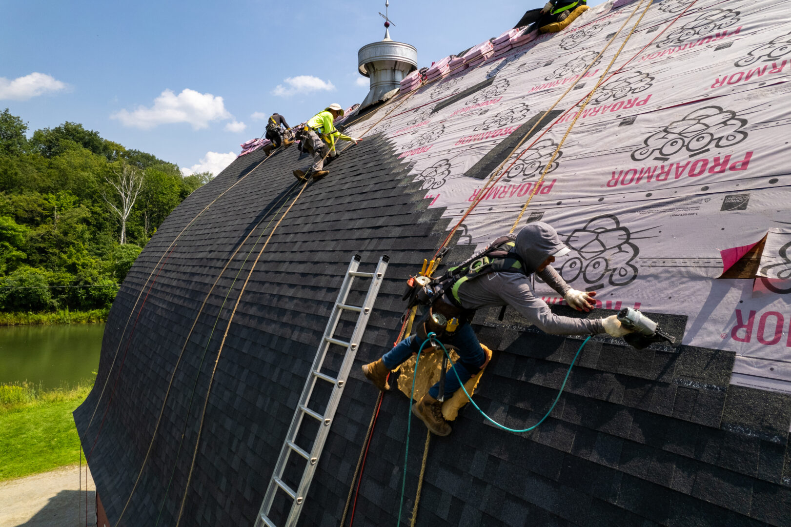 Roofers working safely on a roof using personal fall arrest systems (PFAS)