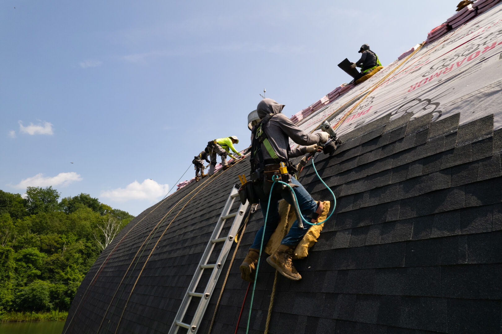 Roofer putting shingles on a roof and wearing appropriate PPE