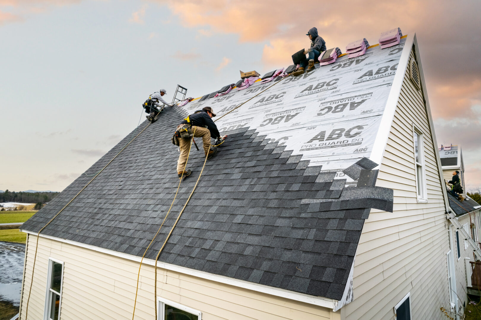 Roofers working on replacing the asphalt shingle roof of a house