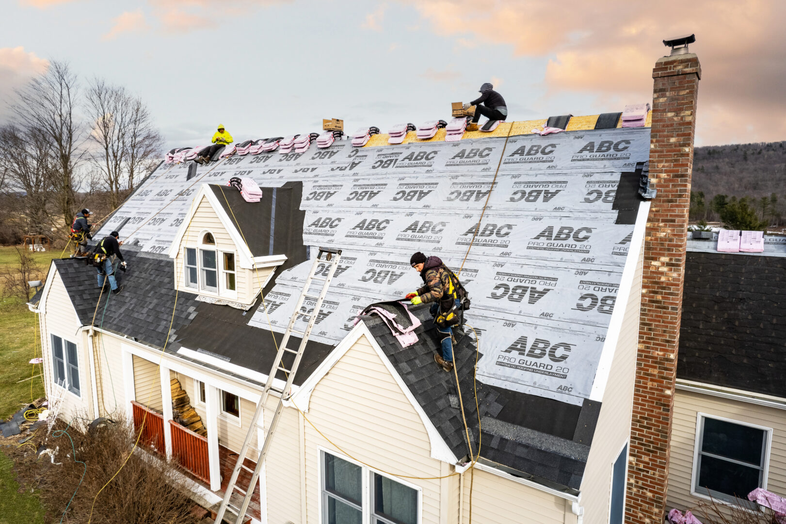 Roofers working on a new asphalt shingle roof on a cape style house in New Haven, Vermont