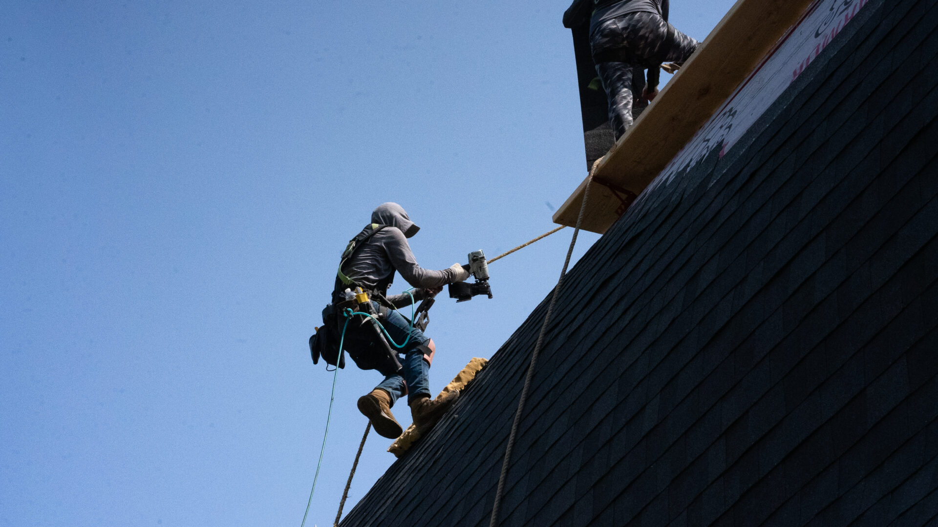 Roofer using a personal fall arrest system (PFAS) while working on a roof