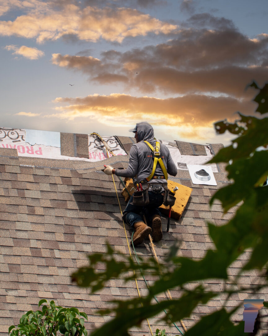 Worker on a roof wearing a harness as a personal fall arrest system (PFAS)