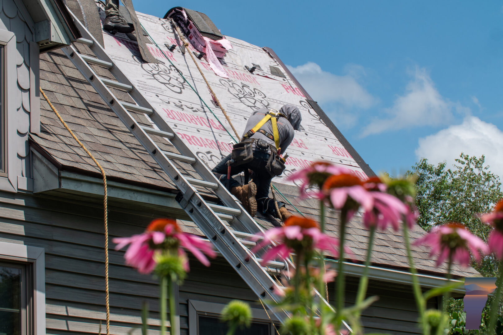Roofer working on a roof next to a ladder