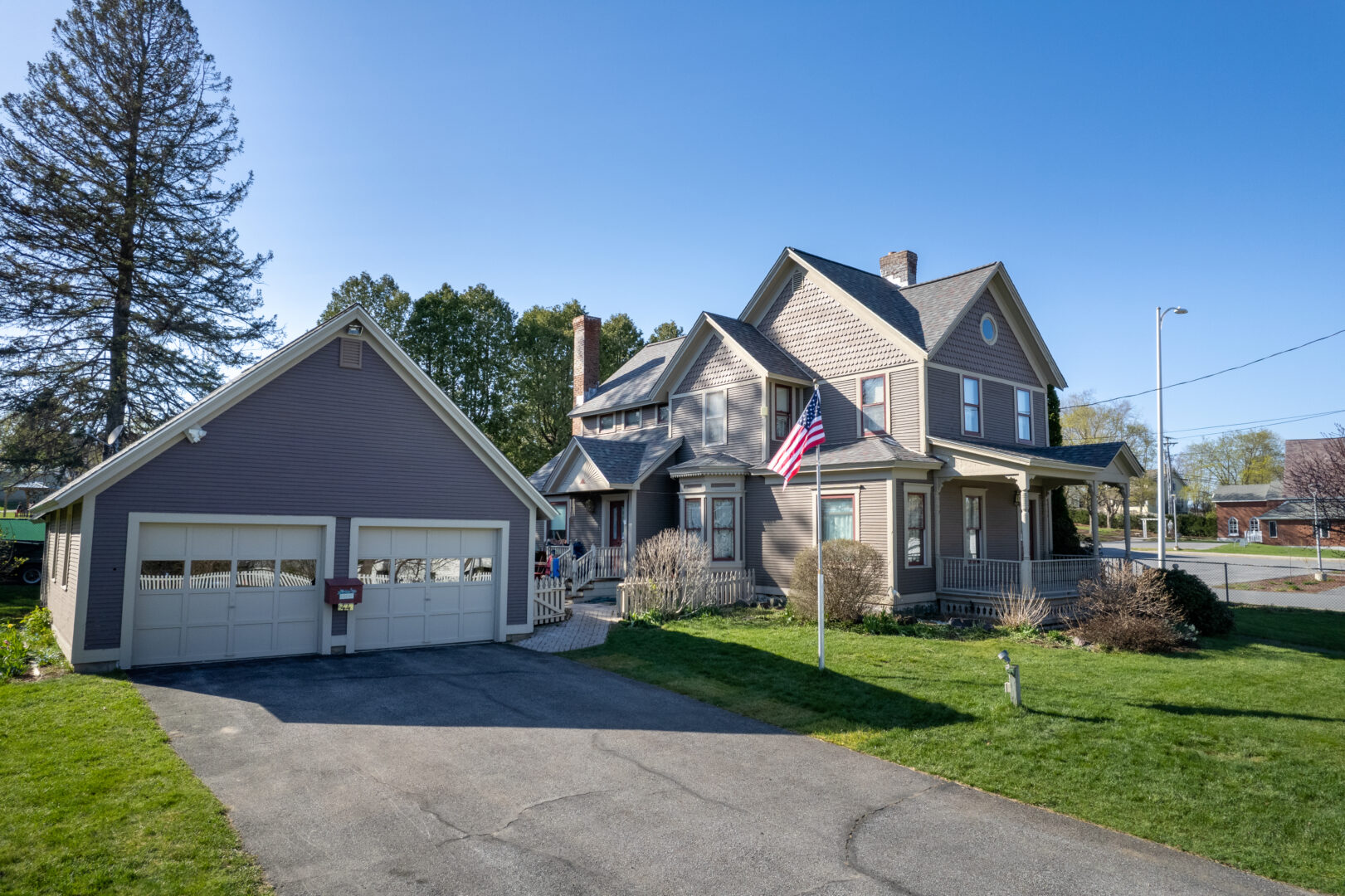 A two-story home and two-car garage that have recently undergone an asphalt shingle roof replacement in Essex Junction, VT. 