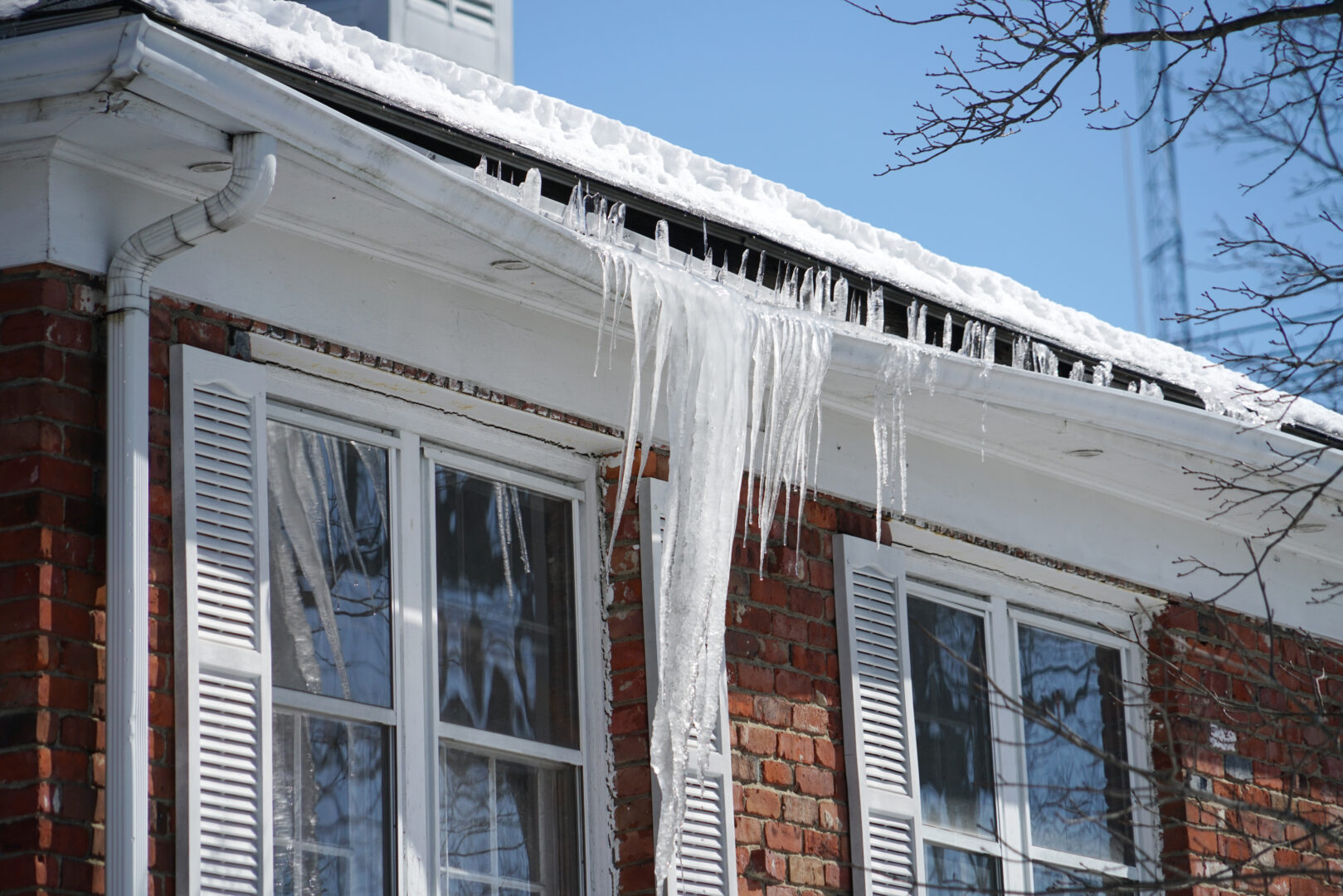 An older brick house with an ice dam forming in the roof gutter