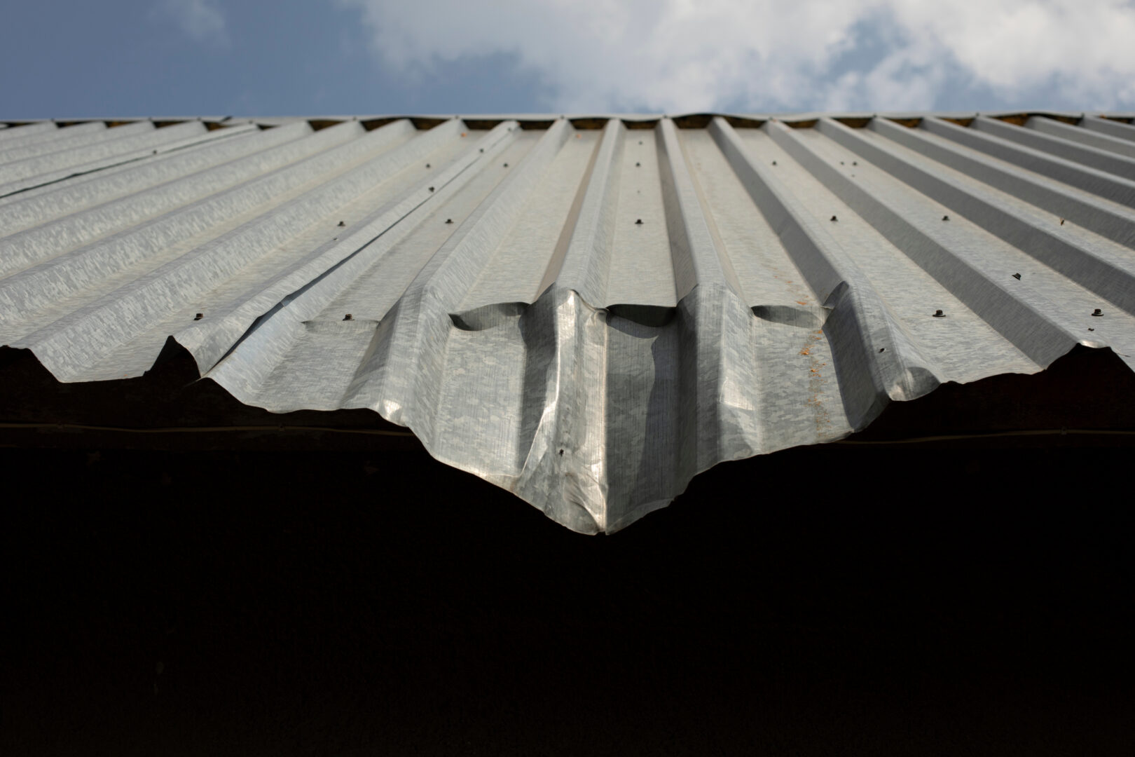 Wind damaged metal roof with a bent edge