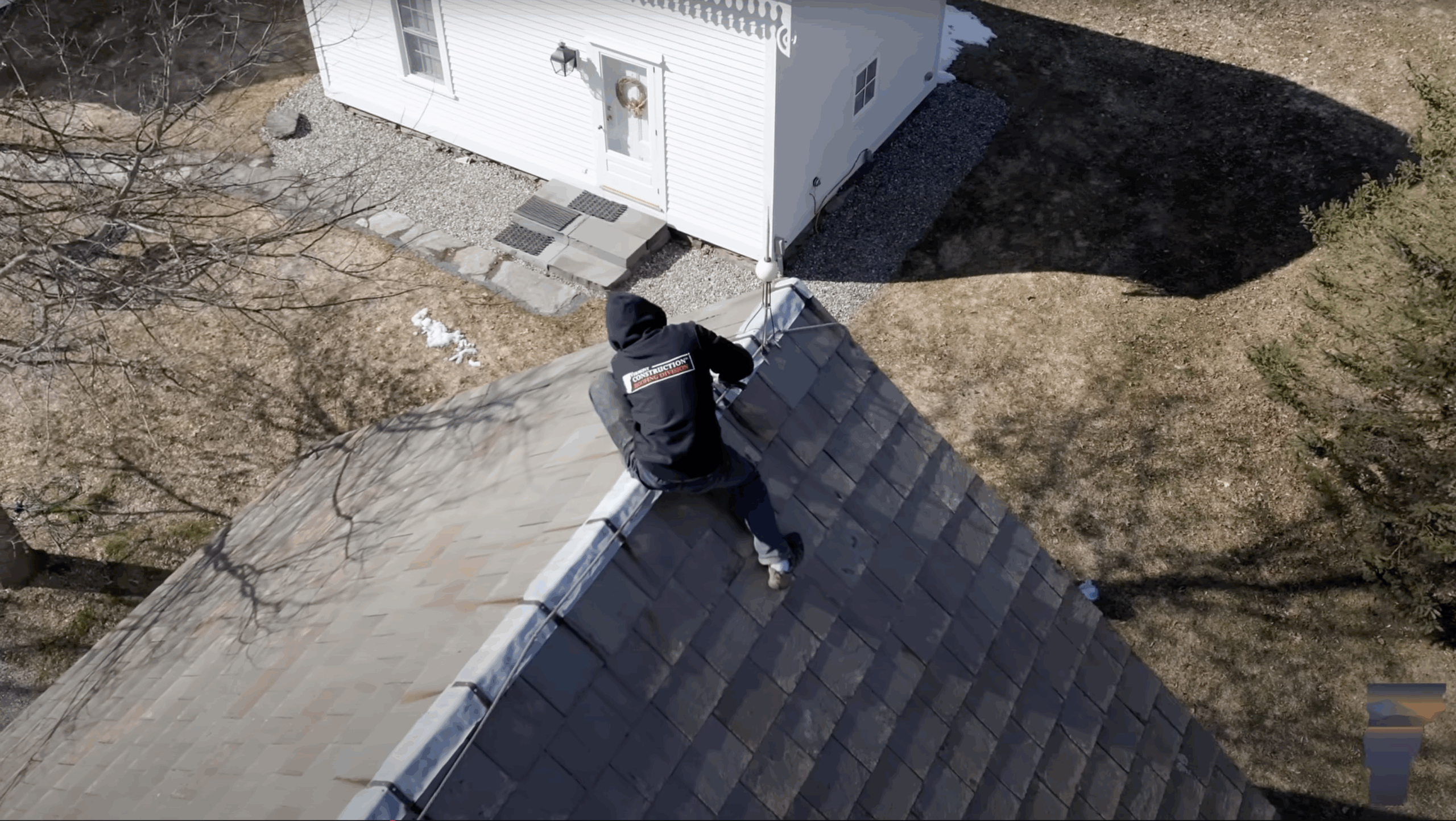 roofer on top of a slate roof working on a roof repair